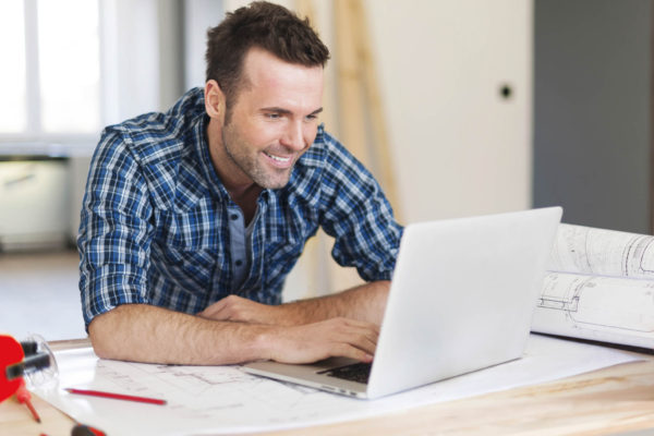 Smiling construction worker working with laptop