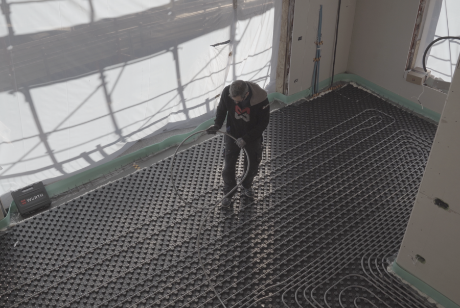 operaio che lavora alla costruzione di una pavimentazione riscaldata.